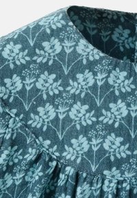 Blue floral-patterned fabric with a textured finish, features a round neckline and gathered detailing along the hem.
