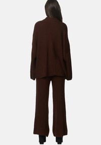 Pull en maille marron et pantalon évasé assorti. Caractéristiques : texture côtelée, coupe ample et manches larges. Aucune fermeture visible.