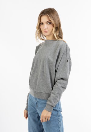 Grå sweatshirt med rund halsudskæring, afslappet pasform, ribbede manchetter og kant, samt en lille logo-detalje på venstre ærme. Båret med blå jeans.
