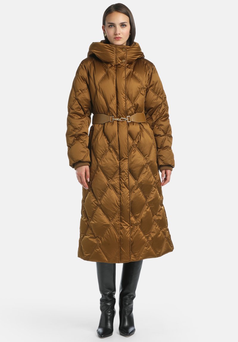 Hnědý prošívaný dlouhý kabát s vysokým límcem, opaskem v pase a žebrovanými manžetami. Nosit s černými vysokými botami ke kolenům, které mají hladký, lesklý povrch.