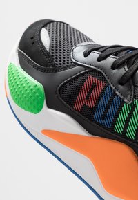 Black athletic shoe with mesh and synthetic upper. Features multicolored accents in red, blue, green, and orange. Thick textured sole.