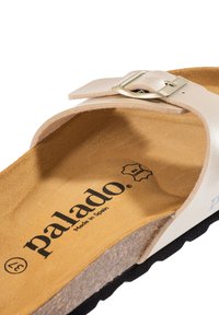Sandalo in pelle beige con cinturino regolabile, soletta in sughero e suola in gomma nera texturizzata. Marchio "palado" visibile sulla soletta. Prodotto in Spagna.