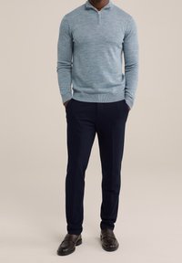 Ljusblå, strukturerad tröja med halvdragkedja. Matchad med mörkblå dressbyxor och mörkbruna loafers. Klassisk passform, slät tyg.