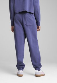 Lilla bomulds sweatpants med en baglomme har en afslappet pasform og elastiske manchetter. Sammen med lyse sneakers.