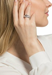 Anello in argento con dettagli intricati, posizionato su un dito, che mostra un design intrecciato e una finitura lucida e liscia.