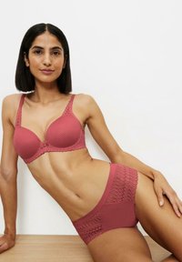 Roze lingerieset met een gepadded beha van textuurstof en kantdetails, gecombineerd met een bijpassende slips, beide in een coördinerende kleur.