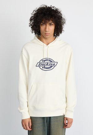 Cremefarvet hoodie med en frontlomme og ribbede manchetter. Indeholder et blåt logo med et cirkulært rebdesign og teksten "Dickies."