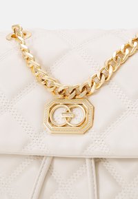 Quilted cream leather purse with gold chain strap and decorative gold clasp featuring interlocking rings and ALDO logo.