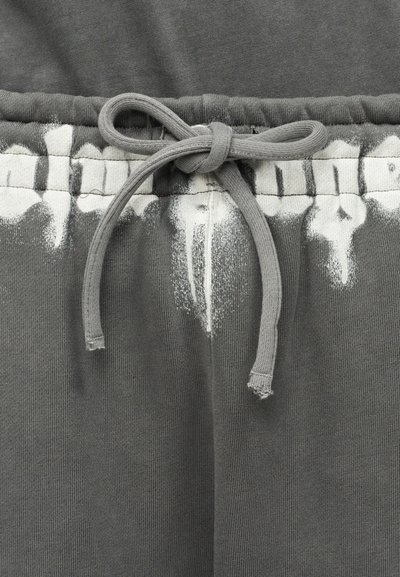 Γκρι φόρμα με κορδόνι στη μέση, που διαθέτει ένα ελαφρύ λευκό εφέ tie-dye κοντά στο τελείωμα, μαλακή υφή και χαλαρή εφαρμογή.