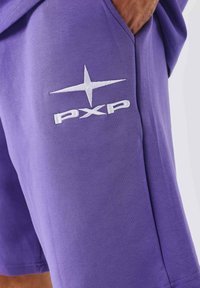 Paarse katoenen shorts met een witte geborduurde logo "PXP" en een sterdesign op het linkerpunt, met zijzakken.