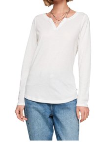 Långärmad vit skjorta med V-halsdesign, tillverkad av ett lätt material, med en rundad nederkant och bärs med blå jeans.