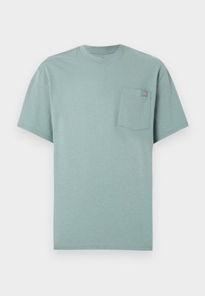 Hellgrünes T-Shirt mit kurzen Ärmeln und Rundhalsausschnitt, mit einer Brusttasche, die ein kleines orange-blaues Logofähnchen trägt.