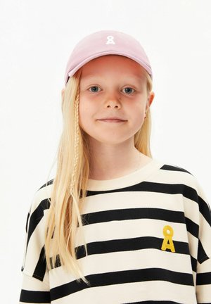 Jong meisje met lang blond haar en een zijvlecht, draagt een roze pet en een zwart-wit gestreept shirt met een geel embleem.
