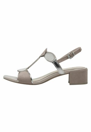 Beige og sølv åben tå damesandal med cirkulære stropdetaljer, lav blokhæle og justerbar ankelspænde.