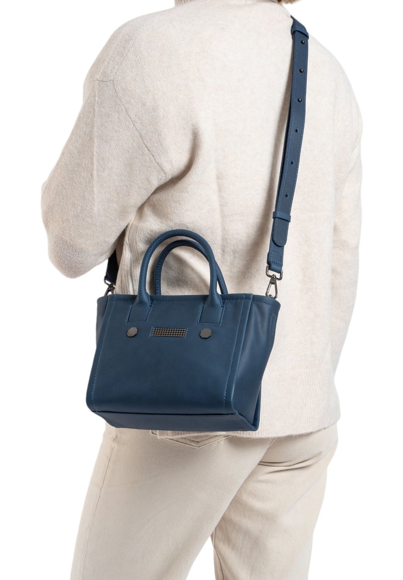 Sac à main en cuir bleu avec de courtes poignées et une longue bandoulière réglable. Présente des accents en métal noir et un détail texturé horizontal à l'avant.