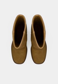 Barna vékony bőr bokacipők sima textúrával és kerek orral. Alacsony, szimmetrikus nyílások a könnyű felvétel érdekében. Minimalista dizájn.