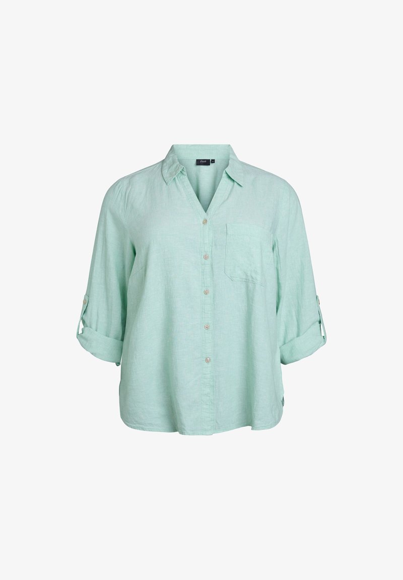 Camisa de lino verde claro con botones en la parte frontal, cuello, bolsillo en el pecho y mangas enrolladas. Presenta un corte relajado y una textura suave.
