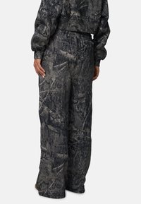 Camouflage joggingsbroek in donkergrijs met natuur geïnspireerde patronen, een elastische tailleband en een ontspannen pasvorm, gemaakt van een zachte, gestructureerde stof.