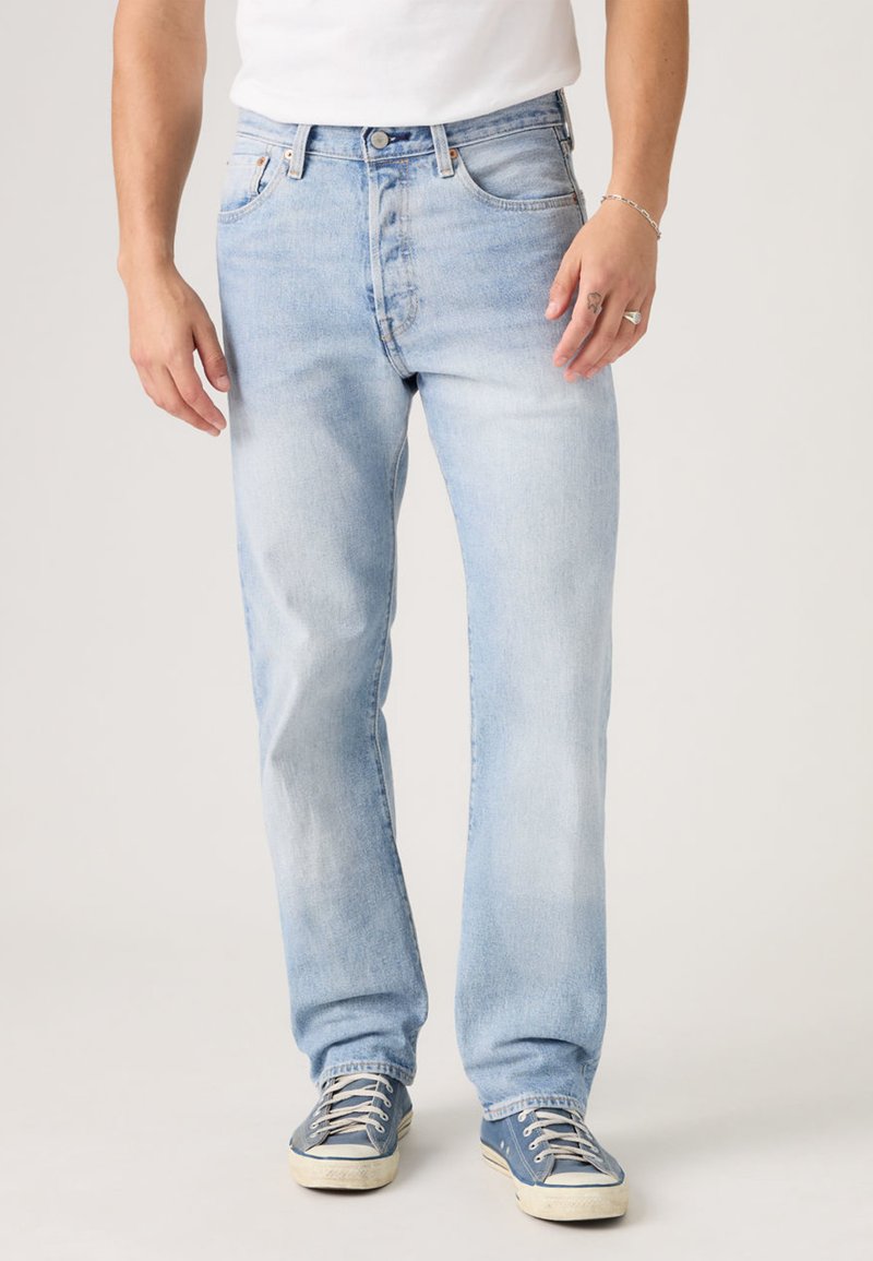 Šviesiai mėlynos spalvos džinsai iš džinso audinio su tiesiomis kojų siūlėmis, penkių kišenių dizainu, viršutiniu mygtuku ir subtiliais pašviesinimais, suteikiančiais dėvėtą išvaizdą.