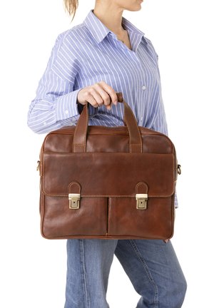Portadocumenti in pelle marrone con due manici superiori, due tasche frontali con fibbie e una superficie texturizzata. Indossato da una persona in una camicia a righe.