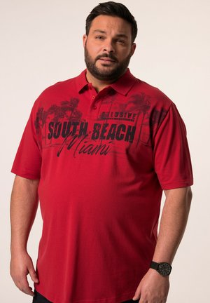 Punainen polo-paita, jossa on kaulus ja lyhyet hihat. Rinnassa on musta graafinen printti "SOUTH BEACH Miami" palmupuiden ääriviivoilla.