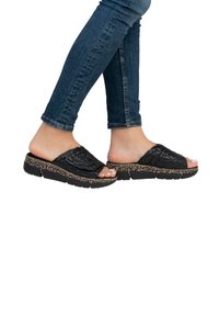 Black slide sandals with a textured woven strap, cork-like midsole, and thick rubber sole, featuring a patterned accent around the base.