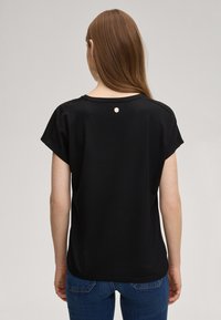 Top nero a maniche corte con scollo tondo. Presenta un piccolo logo sul retro. Realizzato in un tessuto liscio e leggero.