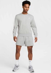 Grå sweatshirt og shorts i matchende stof. Sweatshirten har en rund hals og ribbede manchetter; shortsene har en elastisk talje og diskret branding.