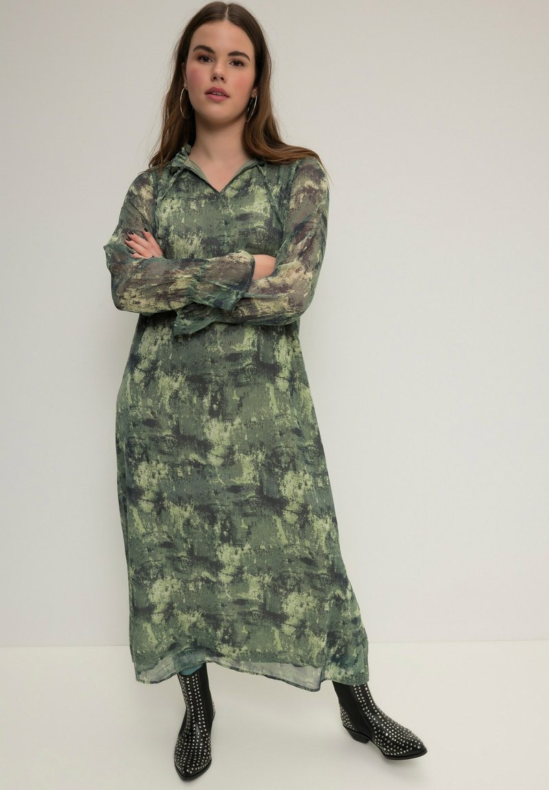 Robe longue et ample dans un motif abstrait vert et noir, fabriquée en tissu léger avec un décolleté en V et des manches longues.