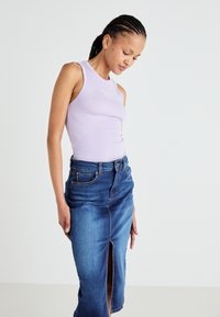 Top a maniche lunghe rib altalena di colore lilla, design aderente. Abbinato a una gonna di jeans a vita alta con uno spacco frontale e un classico lavaggio blu.