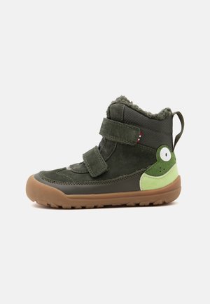 Botte d'hiver pour enfant en vert foncé avec semelle marron, deux bandes Velcro, doublure polaire et motif visage de grenouille sur le talon.
