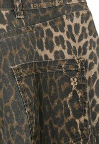 Pantalones cortos de mezclilla con estampado de leopardo en patrón marrón y negro, con un bolsillo trasero cosido y una etiqueta de marca sutil en la pretina.