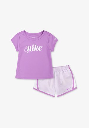 Vijolični atletski komplet, ki vključuje majico s kratkimi rokavi z belim logotipom "nike" in ujemajoče se kratke hlače z elastiko v pasu ter stranskimi detajli.