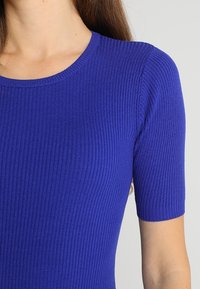 Ribbed, short-sleeve top in vibrant royal blue. Features a round neckline and a textured fabric, offering a snug fit through the bodice.