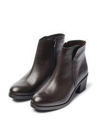 Botas de cuero marrón hasta el tobillo con cierre de cremallera, punta redondeada y tacón cuadrado. Textura suave con detalles de costura a lo largo de las costuras.