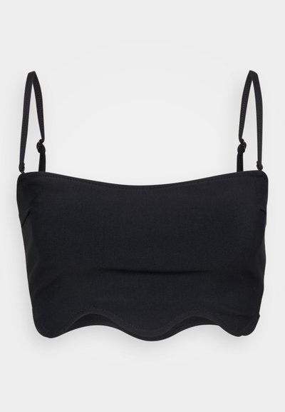 Black bandeau top with adjustable straps, smooth texture, and a scalloped hem. Simple design, suitable for layering or casual wear.