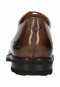 Chaussure habillée en cuir marron avec une texture lisse, un talon arrondi et des détails de couture subtils. Présente un marquage à l'arrière. Semelle en caoutchouc.