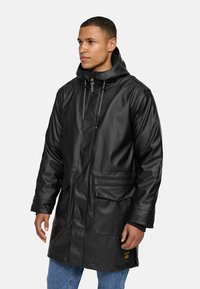 Zwarte, waterdichte parka met een capuchon, front rits, koord en twee grote voorkruisjes. Gladde textuur en een relaxte pasvorm.
