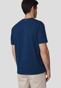 Granatowa, krótko rękawowa koszulka wykonana z bawełny, z okrągłym dekoltem i małym logo nadrukowanym na górnej części pleców.