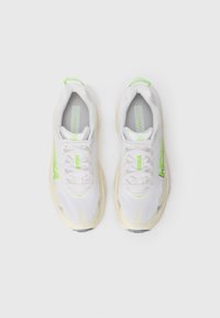 Baskets de sport blanches avec un dessus en mesh texturé, accents vert vif et semelle beige légèrement patternée. Comprend un col rembourré et des lacets.