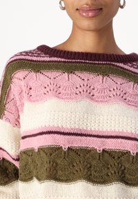 Stickad tröja med växlande horisontella ränder i rosa, krämfärg och olivgrön, med ett texturerat bladmönster och ribbat halsringning.