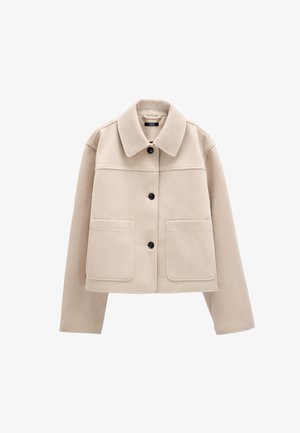 Beżowa krótka kurtka z szerokim kołnierzem, trzema czarnymi guzikami z przodu, długimi rękawami i dwoma dużymi przednimi kieszeniami.