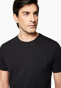 Czarna bawełniana koszulka z okrągłym dekoltem, krótkimi rękawami i kieszenią na piersi z dyskretnym logo. Gładka tekstura i dopasowany krój.
