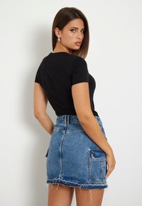 Czarna dopasowana koszulka z krótkim rękawem połączona z niebieską dżinsową spódniczką mini z surowym wykończeniem i bocznymi kieszeniami.