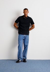 Must musta, helesin sinistes lagedes teksades ja mustades tossudes valgete triipudega. Taust on neutraalne valge, sinine vaip.