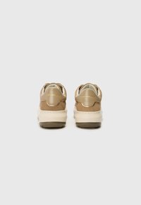 Tan suede sneakers with a cream midsole and soft beige accents. Features a smooth finish and a branded heel tab in gold.
