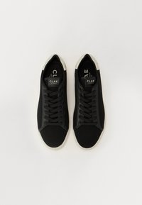 Svarte sneakers med mesh-overdel, flate lisser og rund tå. Har lysegrå detaljer på hælen og gummisålen. Merking synlig.