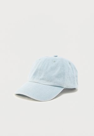 Gorra de béisbol de mezclilla azul claro con visera curvada y orificios de ventilación cosidos, colocada sobre una superficie blanca lisa.