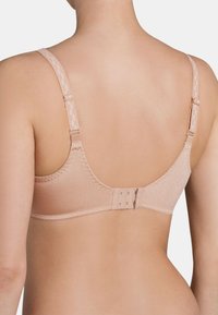 Lichtbeige bh met verstelbare bandjes, gladde stof en een haak-en-oogsluiting. Beschikt over delicate stiksels langs de randen.