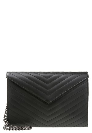 Czarna pikowana kopertówka ze skóry z wzorem w jodełkę i srebrnym łańcuszkiem, umieszczona na białym tle.